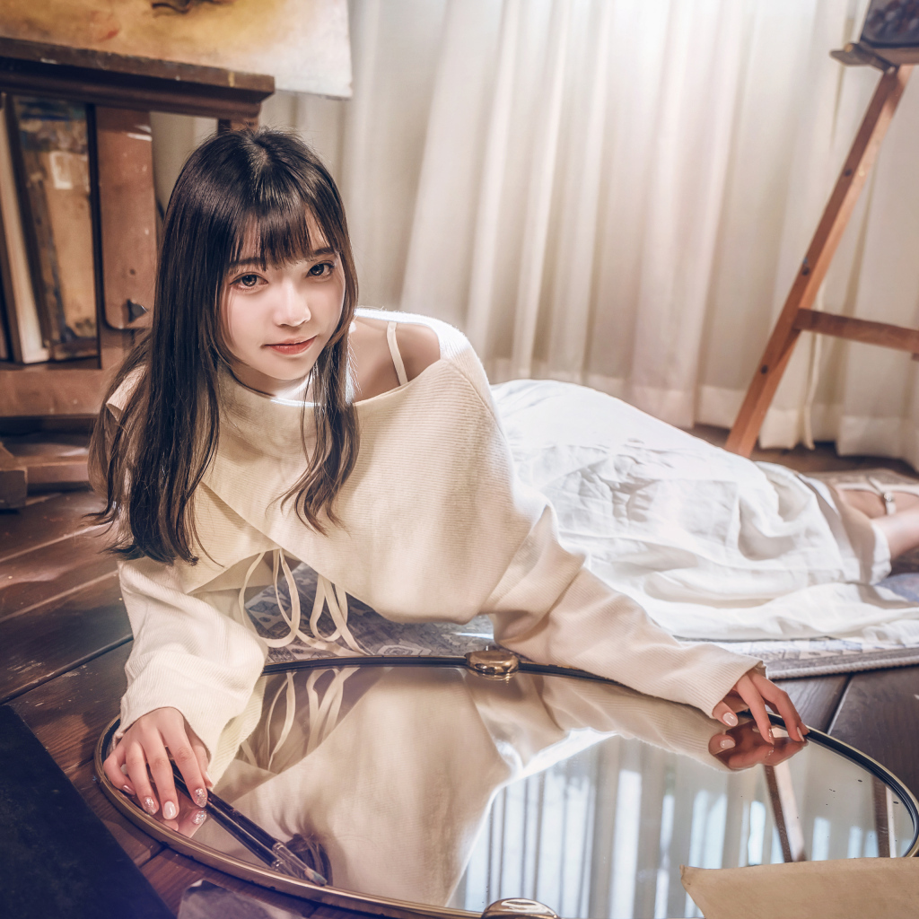 Девушка азиатка в белом платье лежит на полу