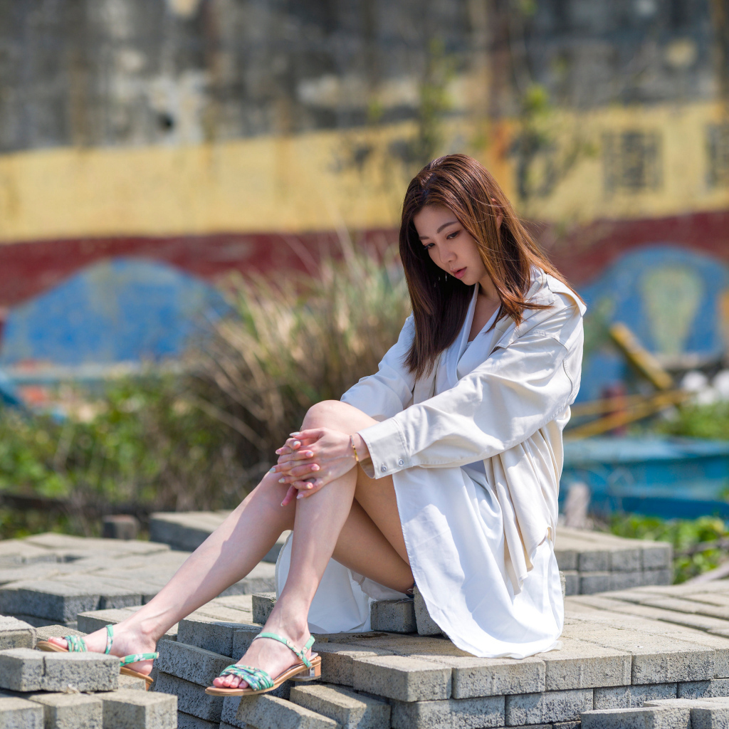 Девушка азиатка в белой рубашке сидит у воды