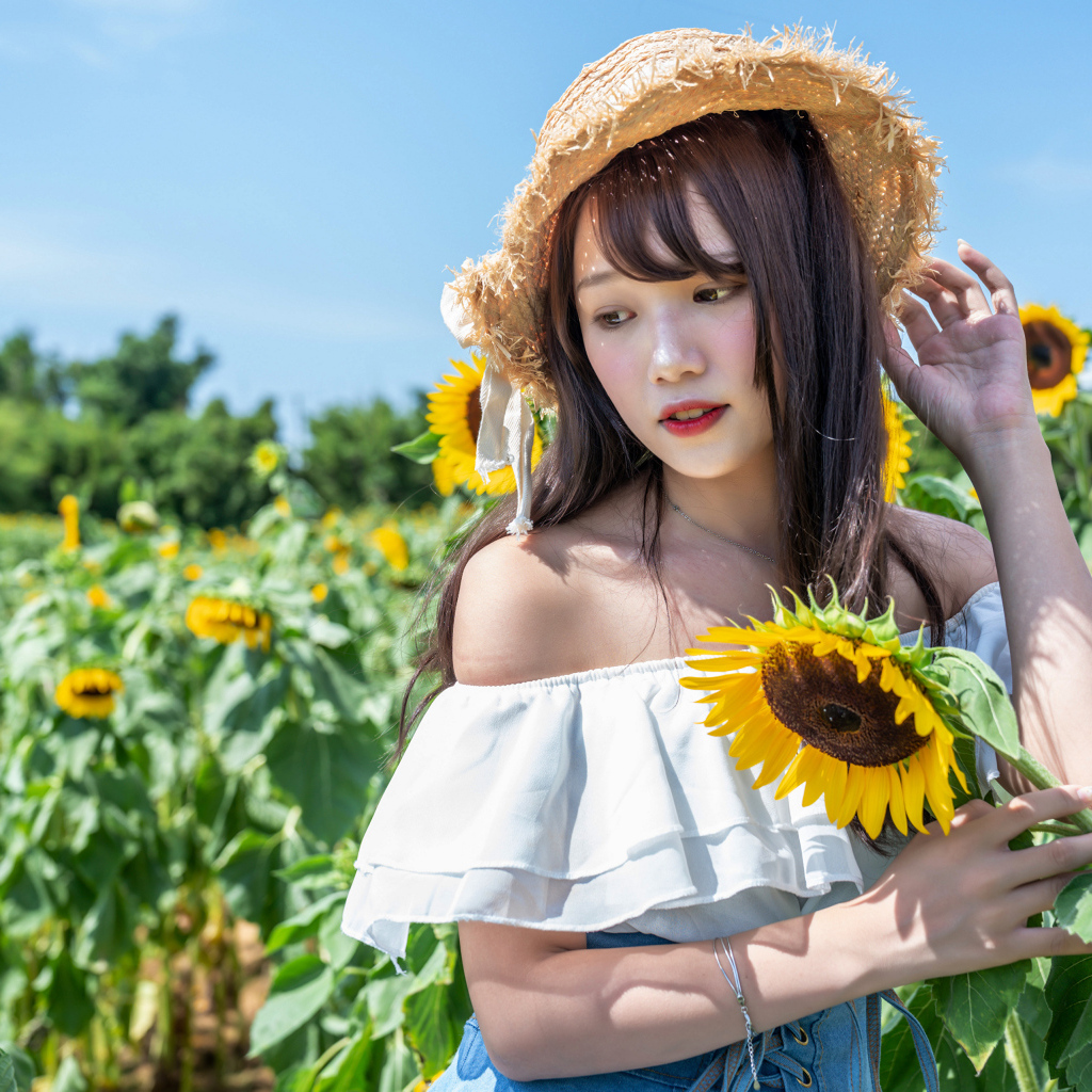 Девушка азиатка на поле с подсолнухами