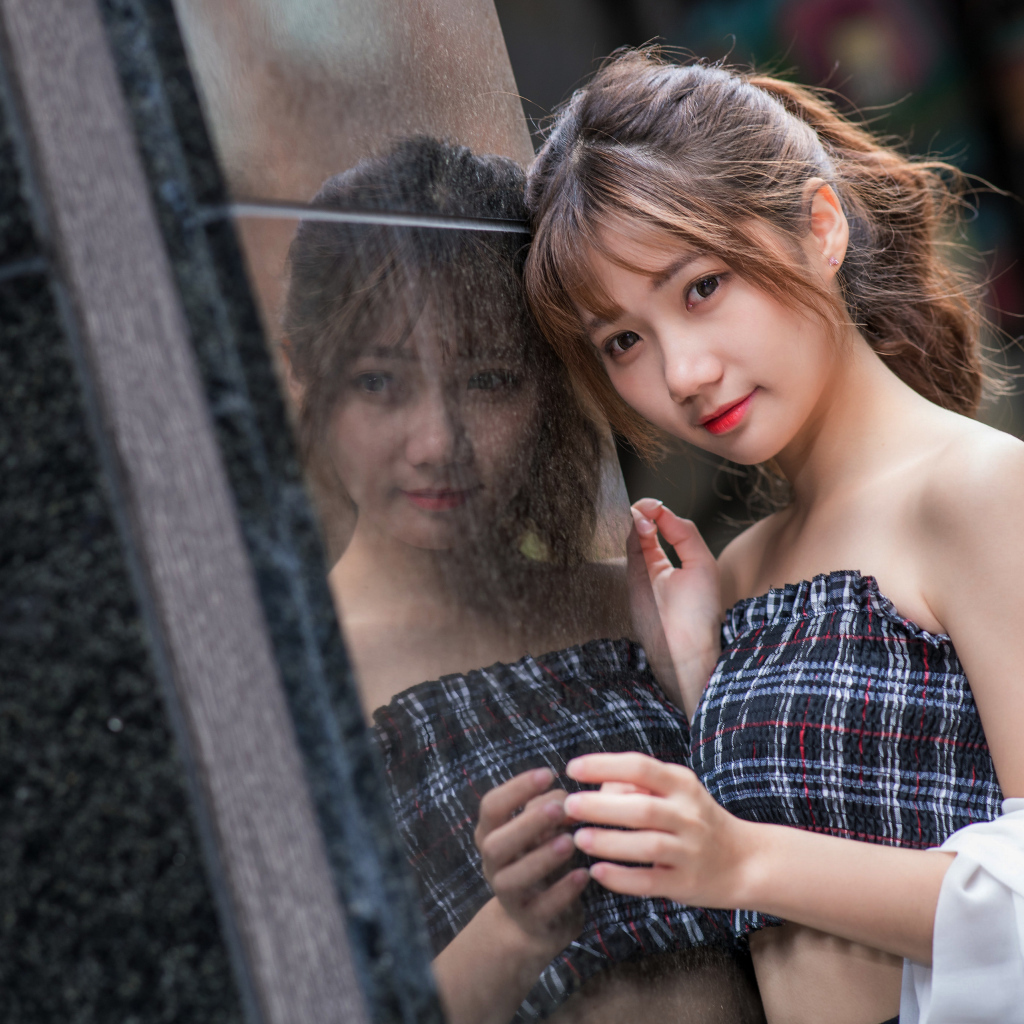 Девушка азиатка отражается в стене