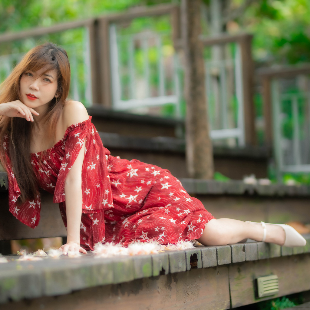 Девушка азиатка лежит на ступеньках в красном платье