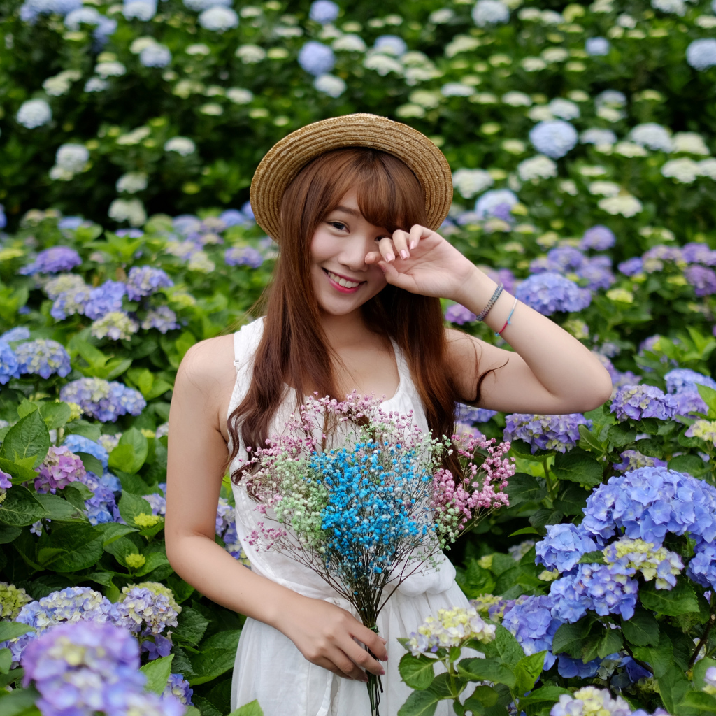 Девушка азиатка у куста с цветами гортензии