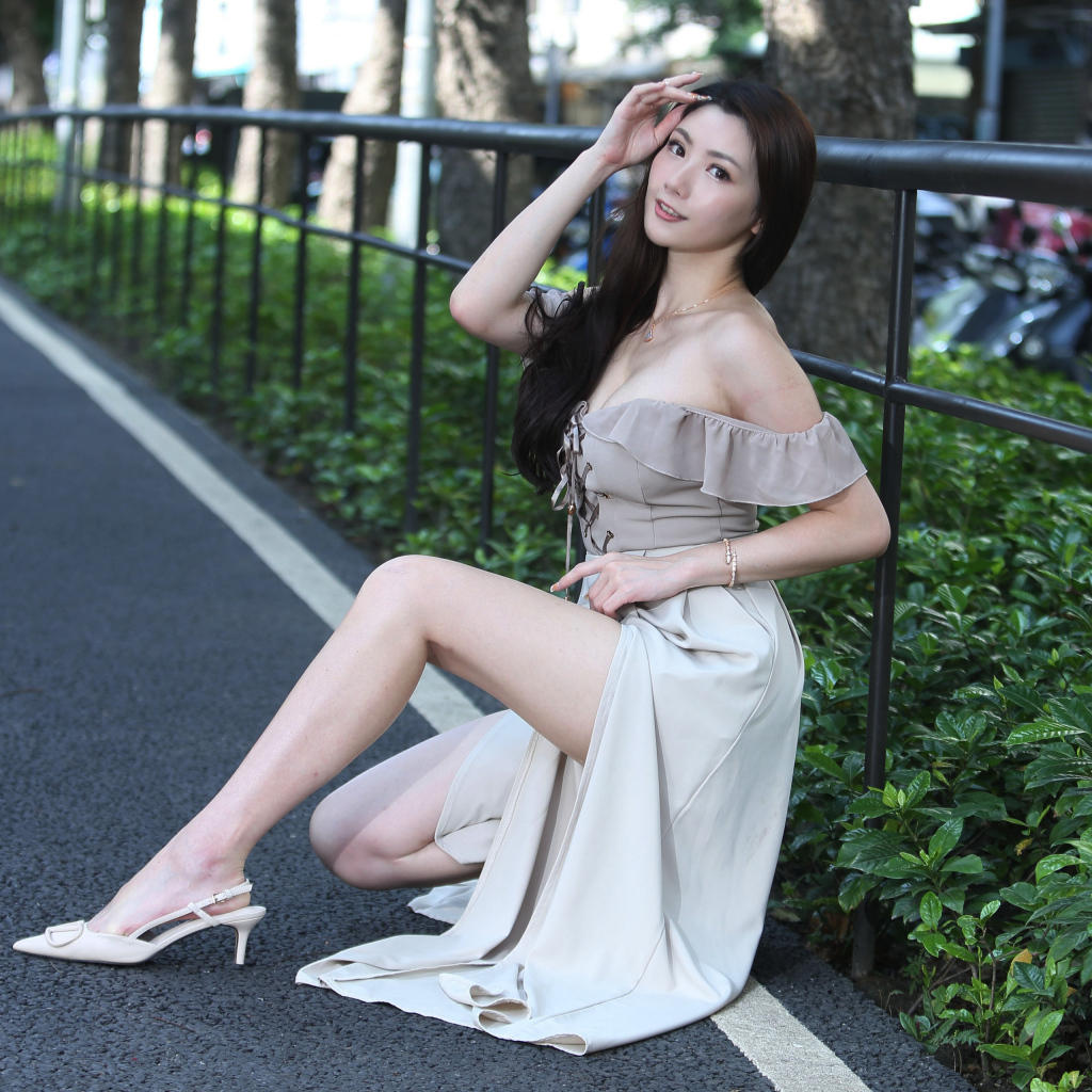 Девушка азиатка сидит у забора