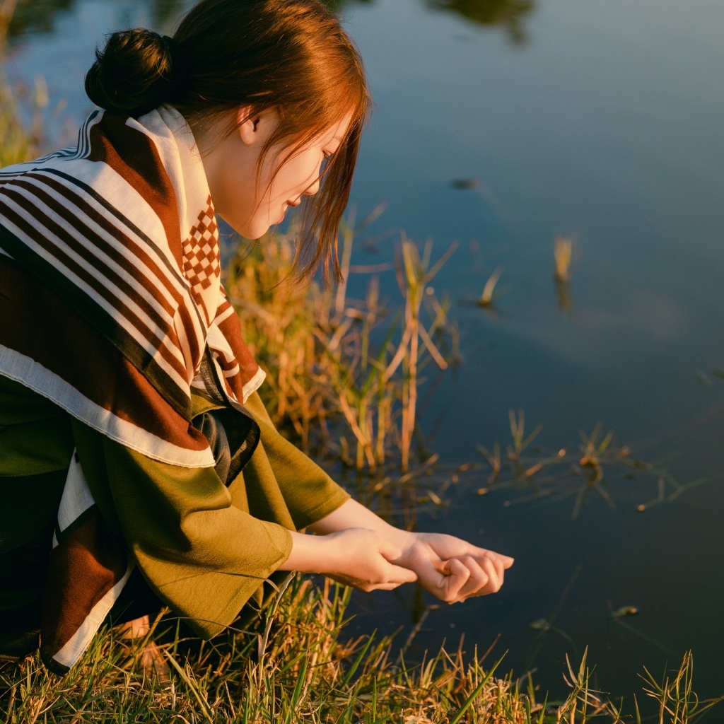 Девушка азиатка сидит у пруда