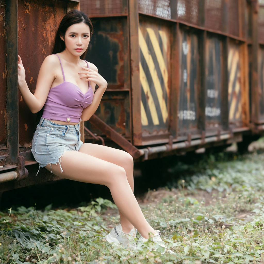 Девушка азиатка сидит у ржавого вагона