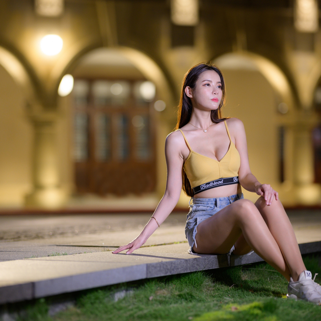 Девушка азиатка сидит на бетонной плите у дома