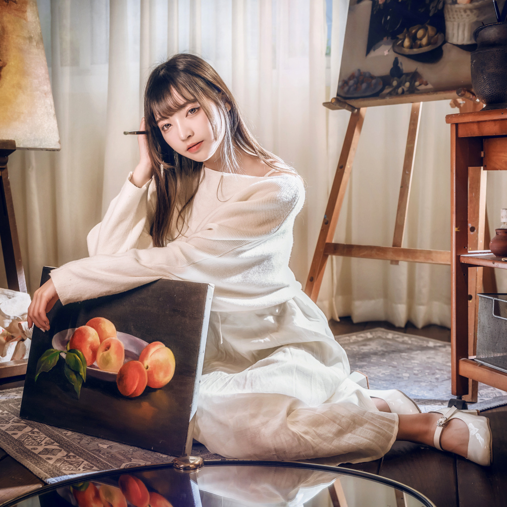 Девушка азиатка сидит с картиной на полу