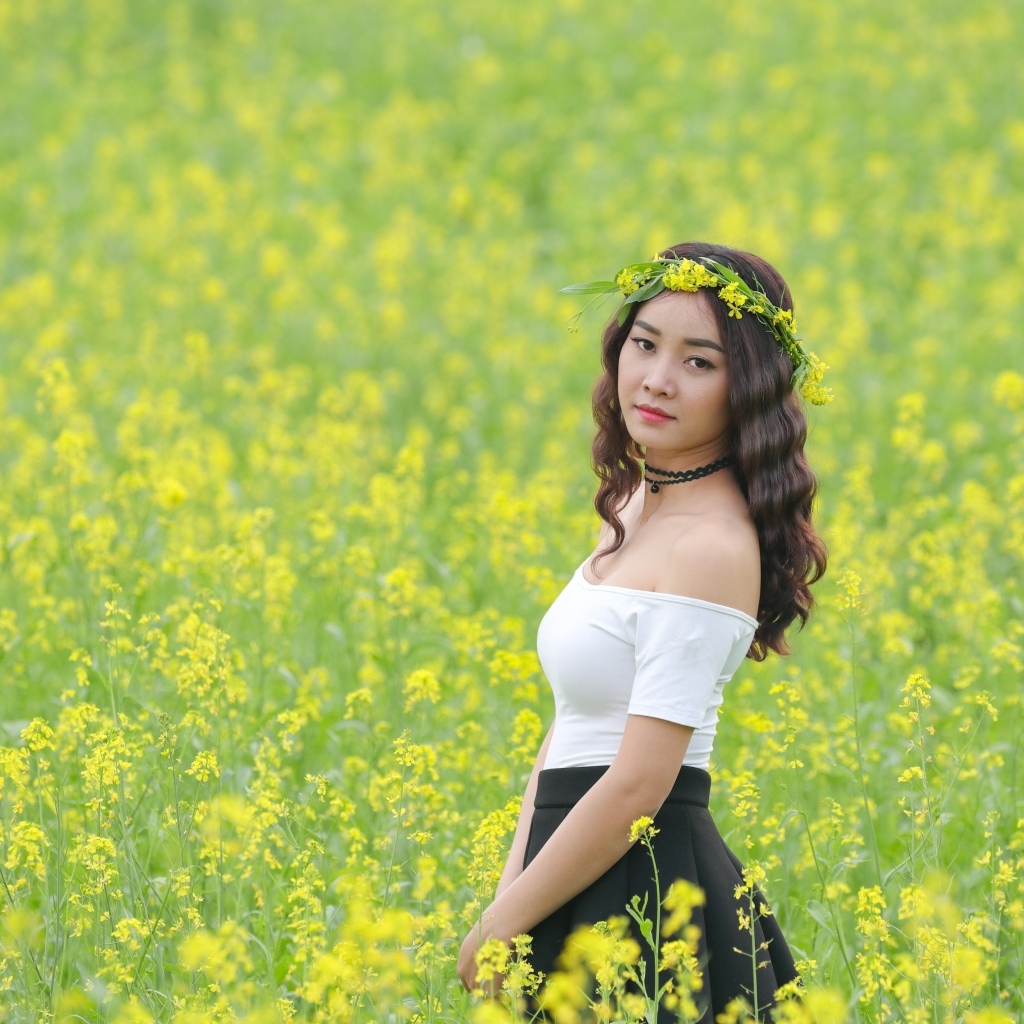 Девушка азиатка стоит на рапсовом поле