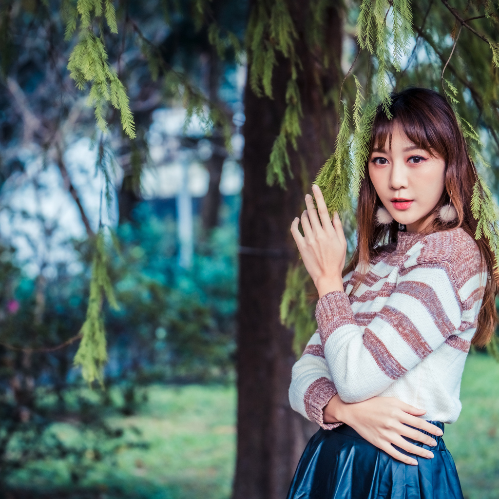 Девушка азиатка стоит у дерева ели