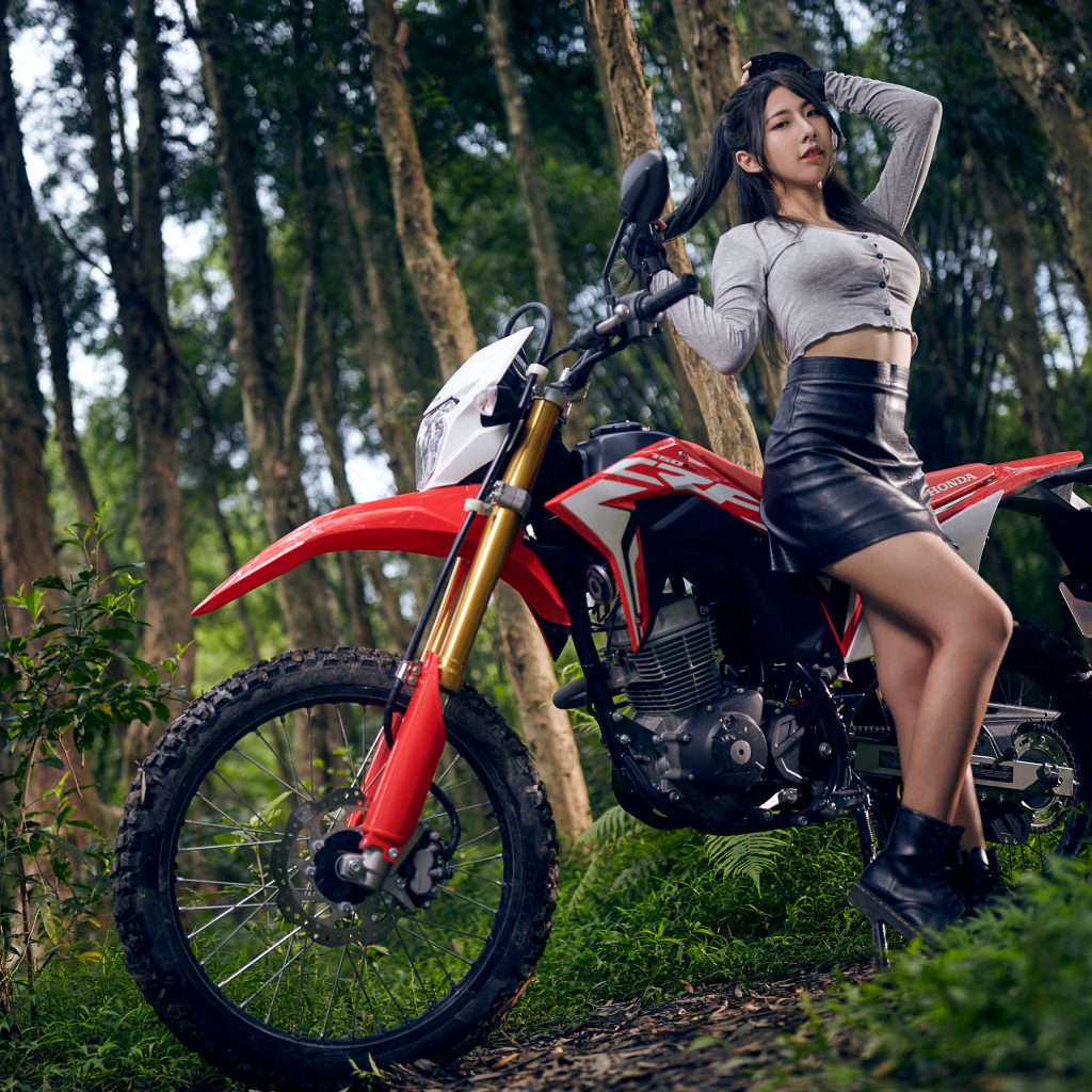 Девушка азиатка с мотоциклом в лесу