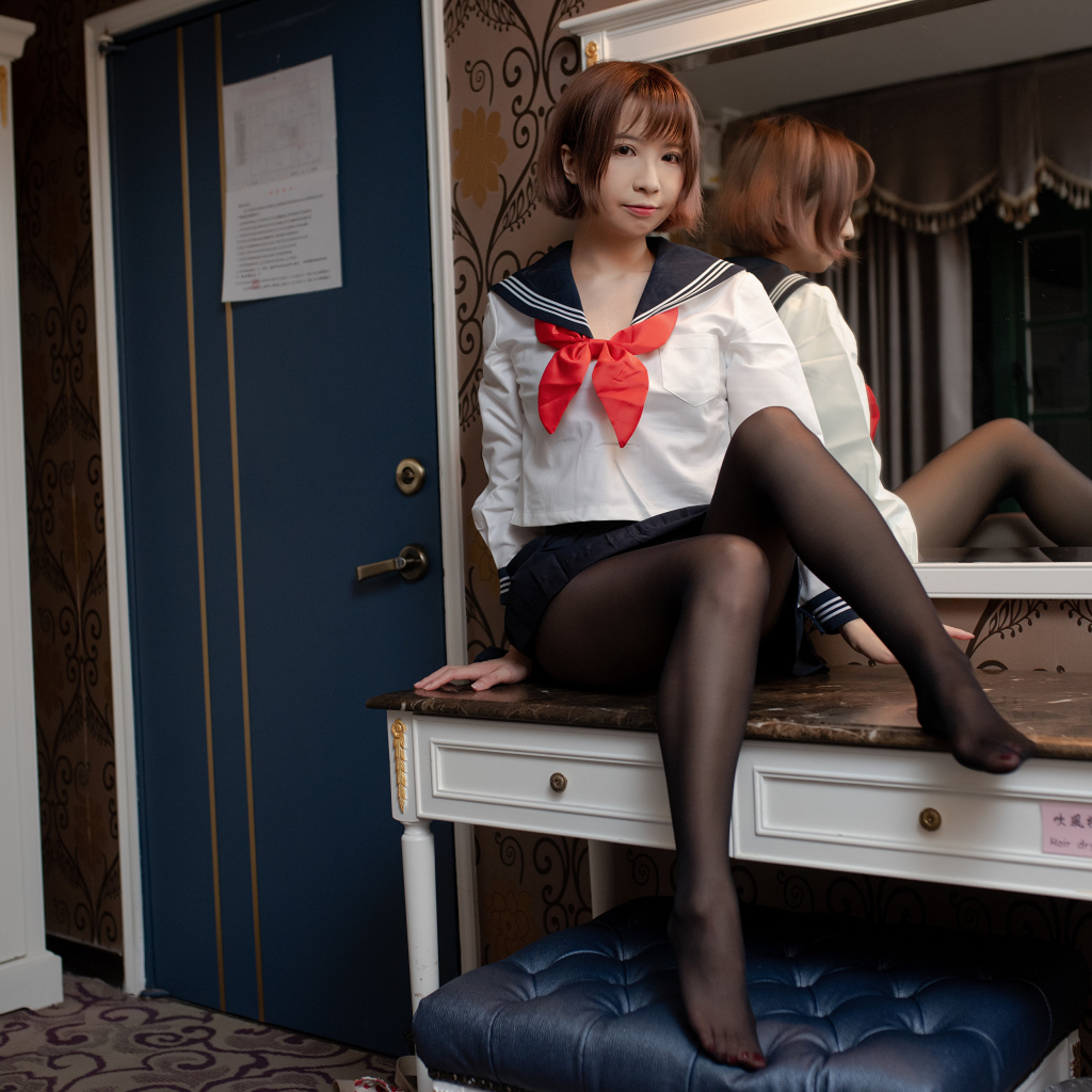 Азиатка в форме сидит на столе