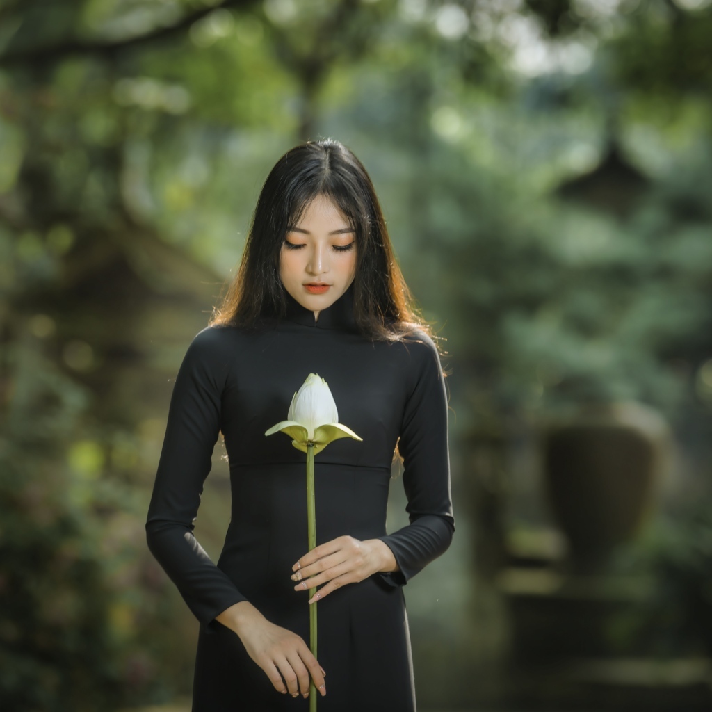 Красивая девушка азиатка в черном платье с цветком лотоса
