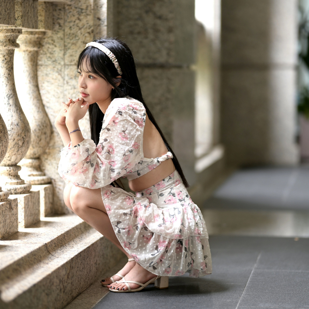 Красивая девушка азиатка в костюме сидит у стены