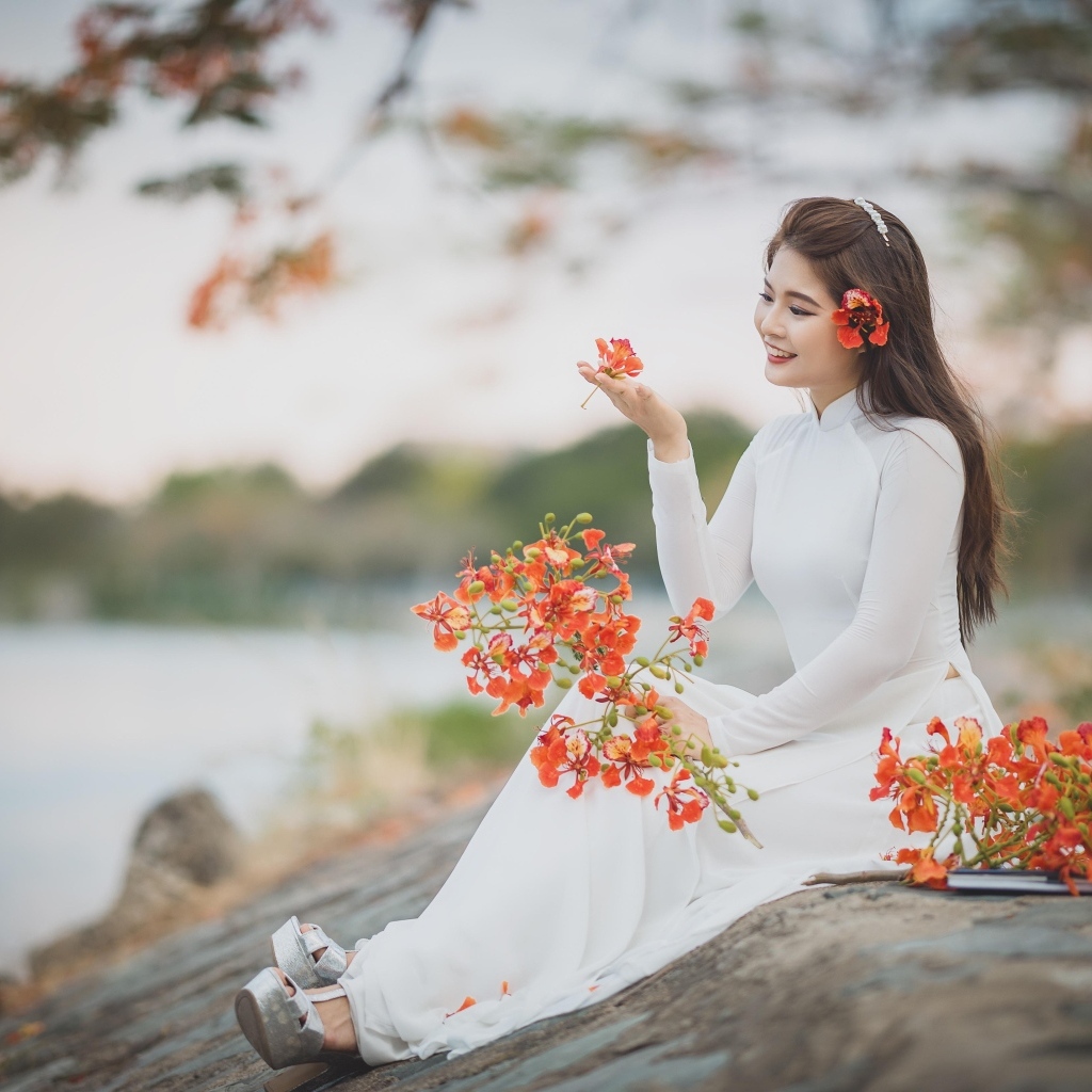 Красивая девушка азиатка в белом платье с цветами в руке