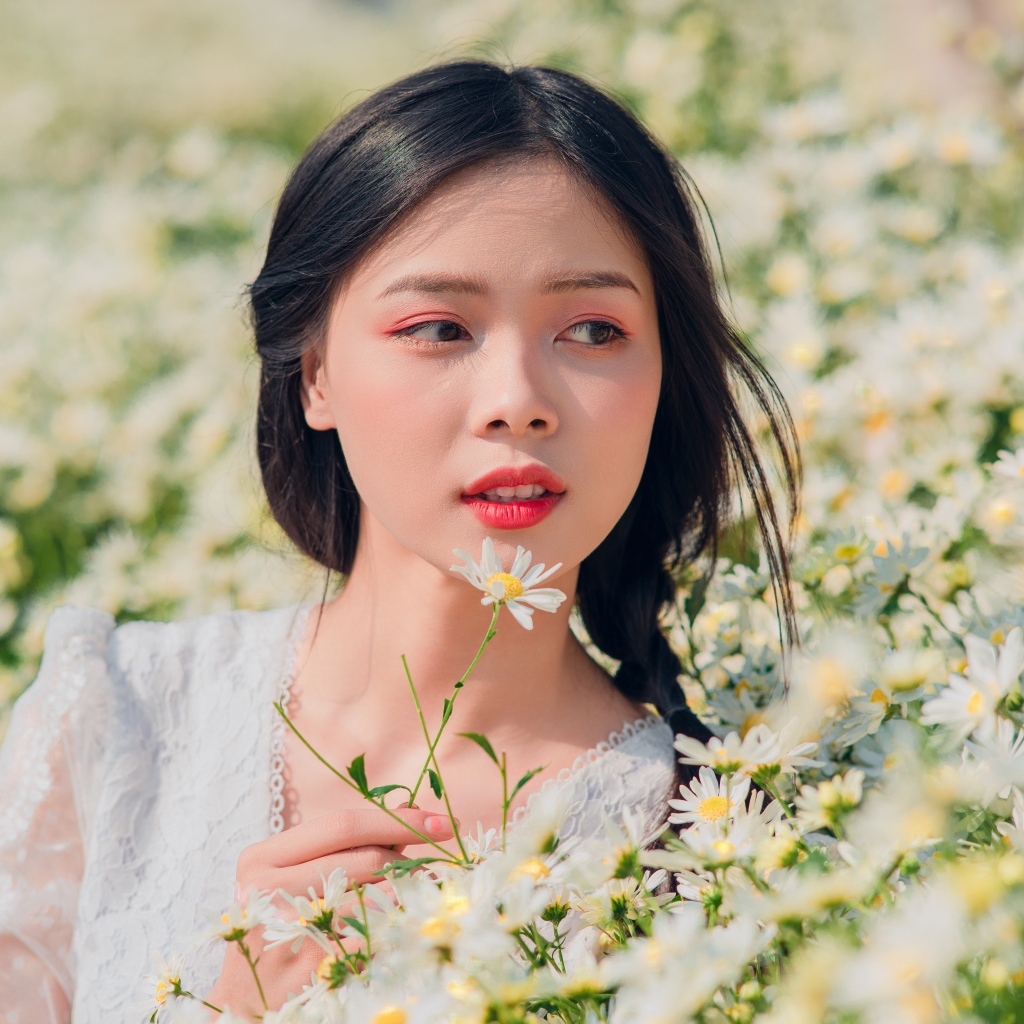 Красивая девушка азиатка на поле с белыми ромашками