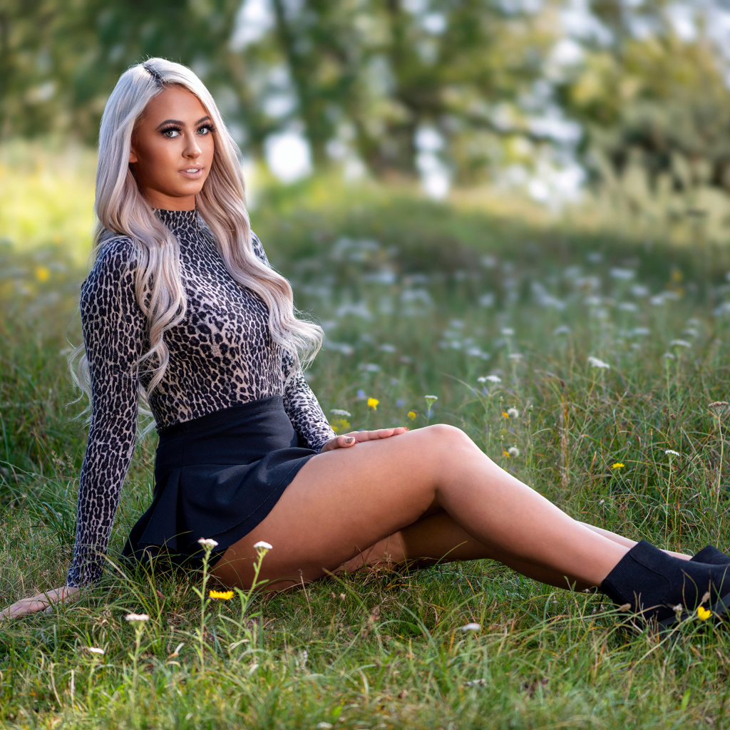 Красивая блондинка в юбке сидит на траве