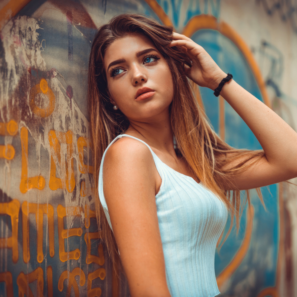 Красивая голубоглазая девушка стоит у стены