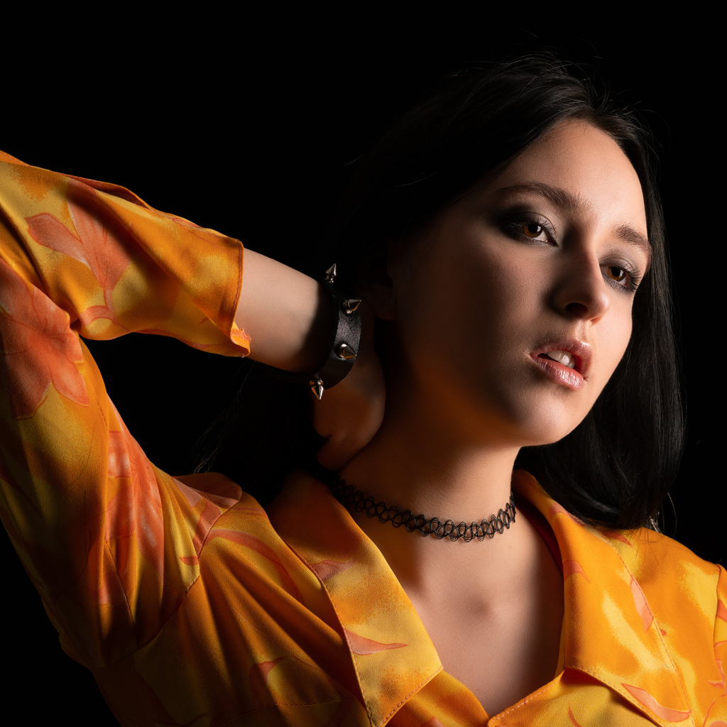 Красивая девушка шатенка с рукой в волосах на черном фоне