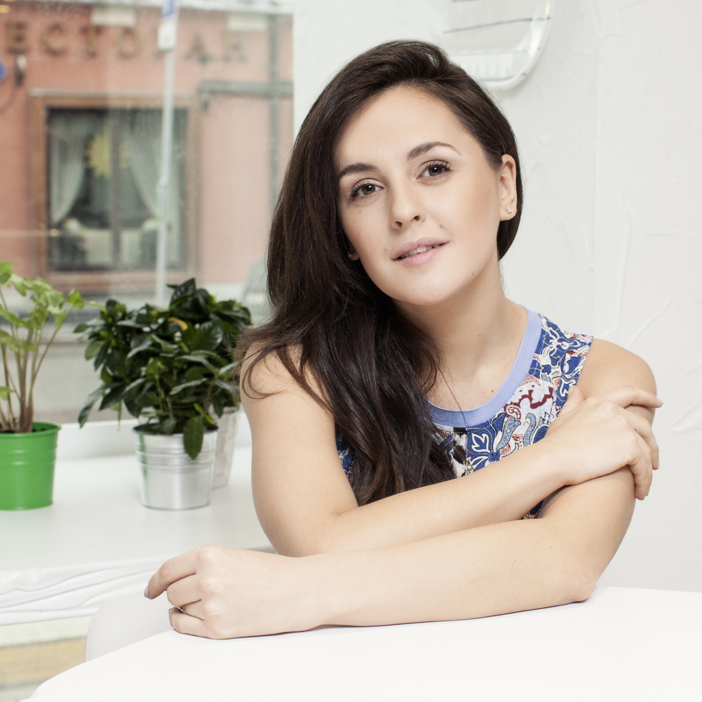 Красивая девушка брюнетка сидит за столиком в кафе 