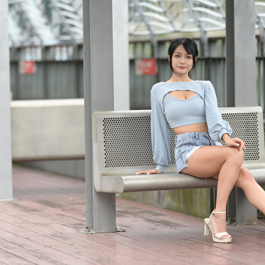 Красивая темноволосая девушка азиатка сидит на лавке