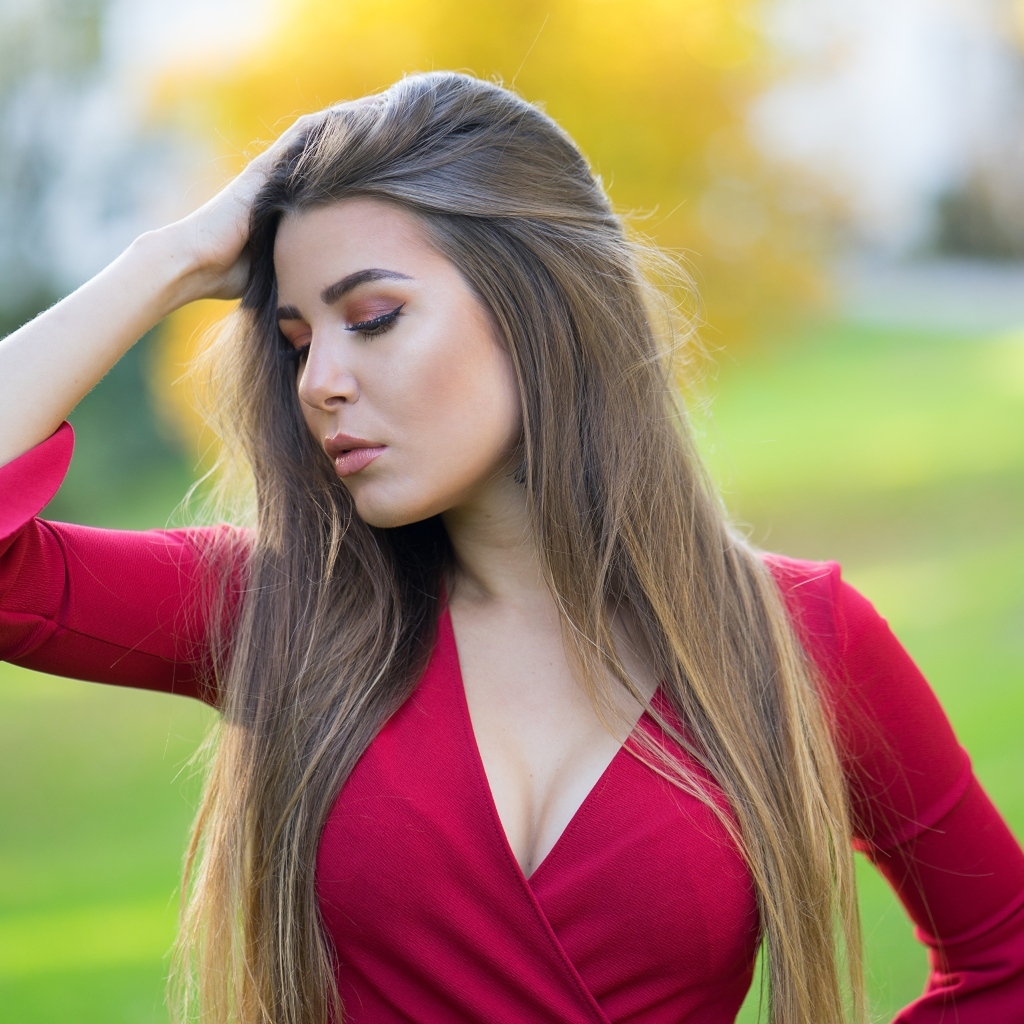 Красивая девушка в красном платье с рукой в волосах