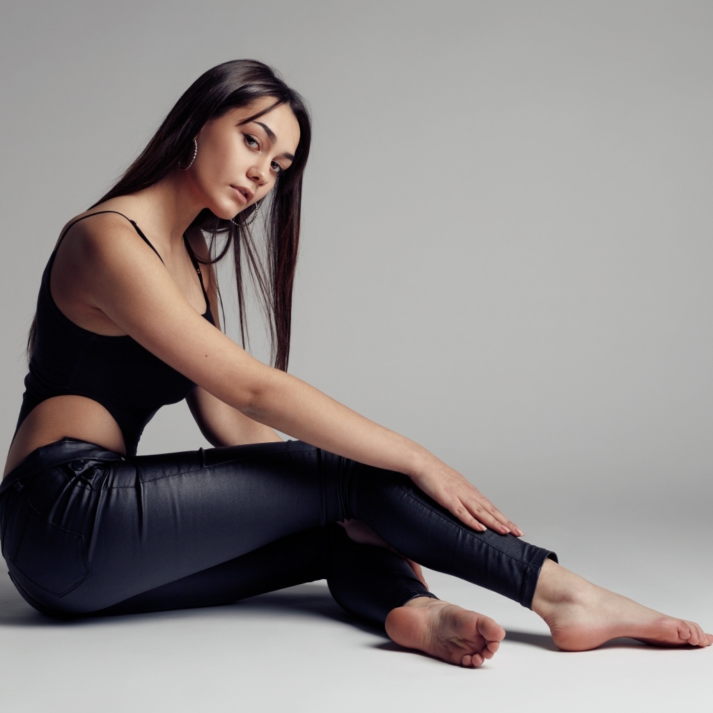 Красивая девушка в черных брюках на сером фоне