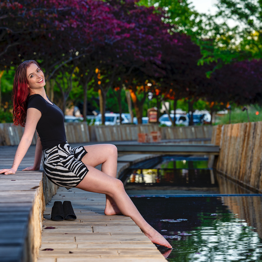 Красивая девушка опустила ноги в воду