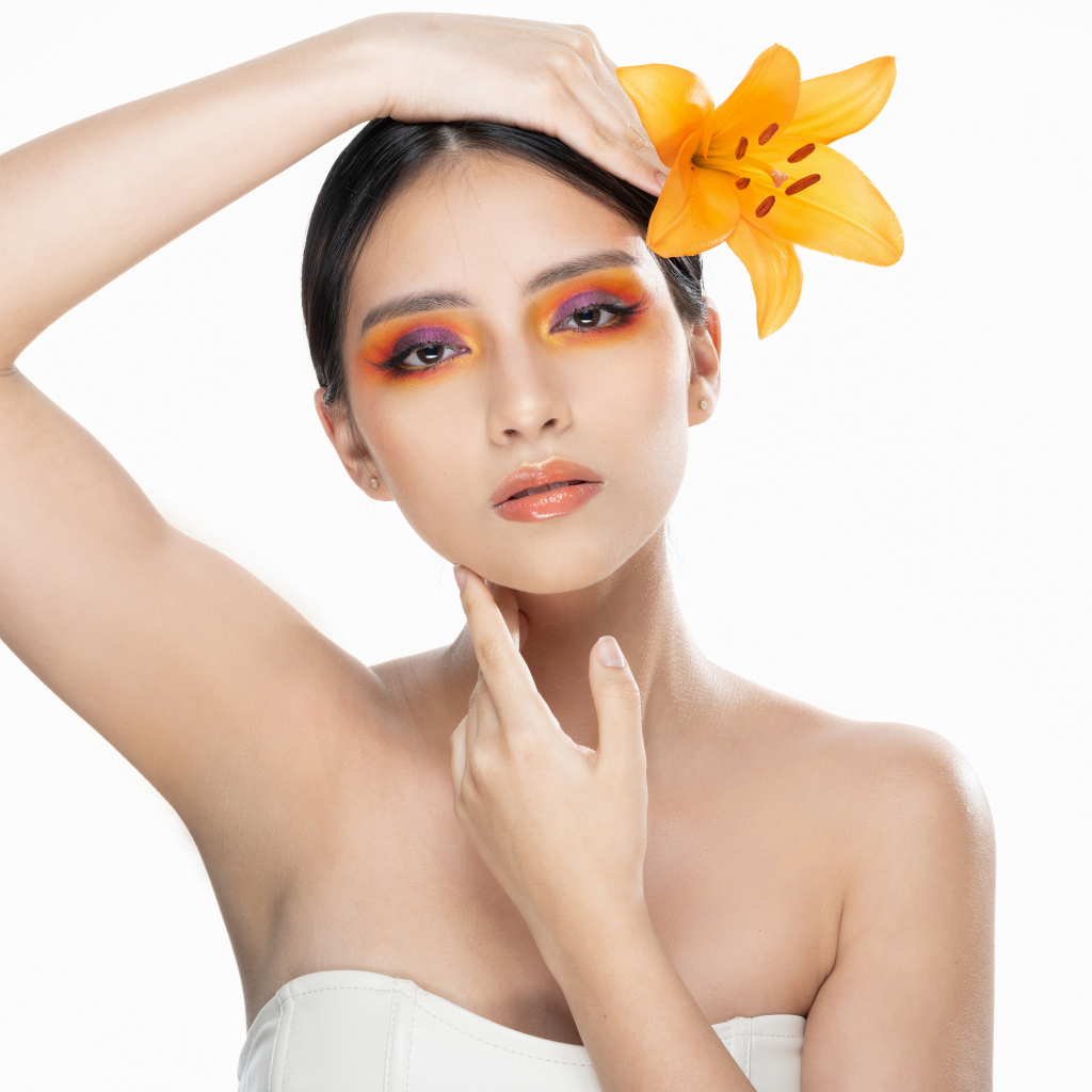 Красивая девушка с цветком лилии в волосах на белом фоне