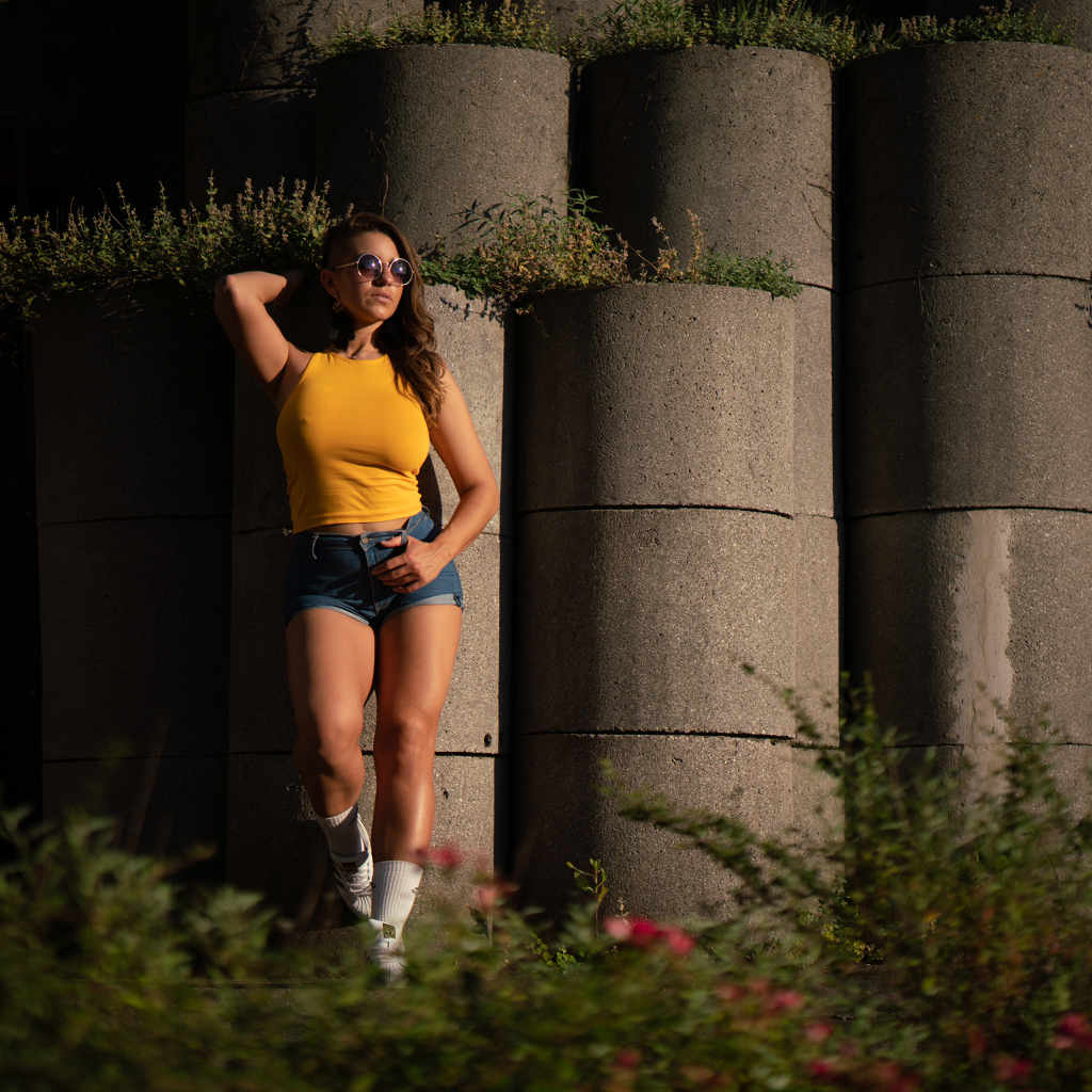 Красивая девушка в очках стоит у стены