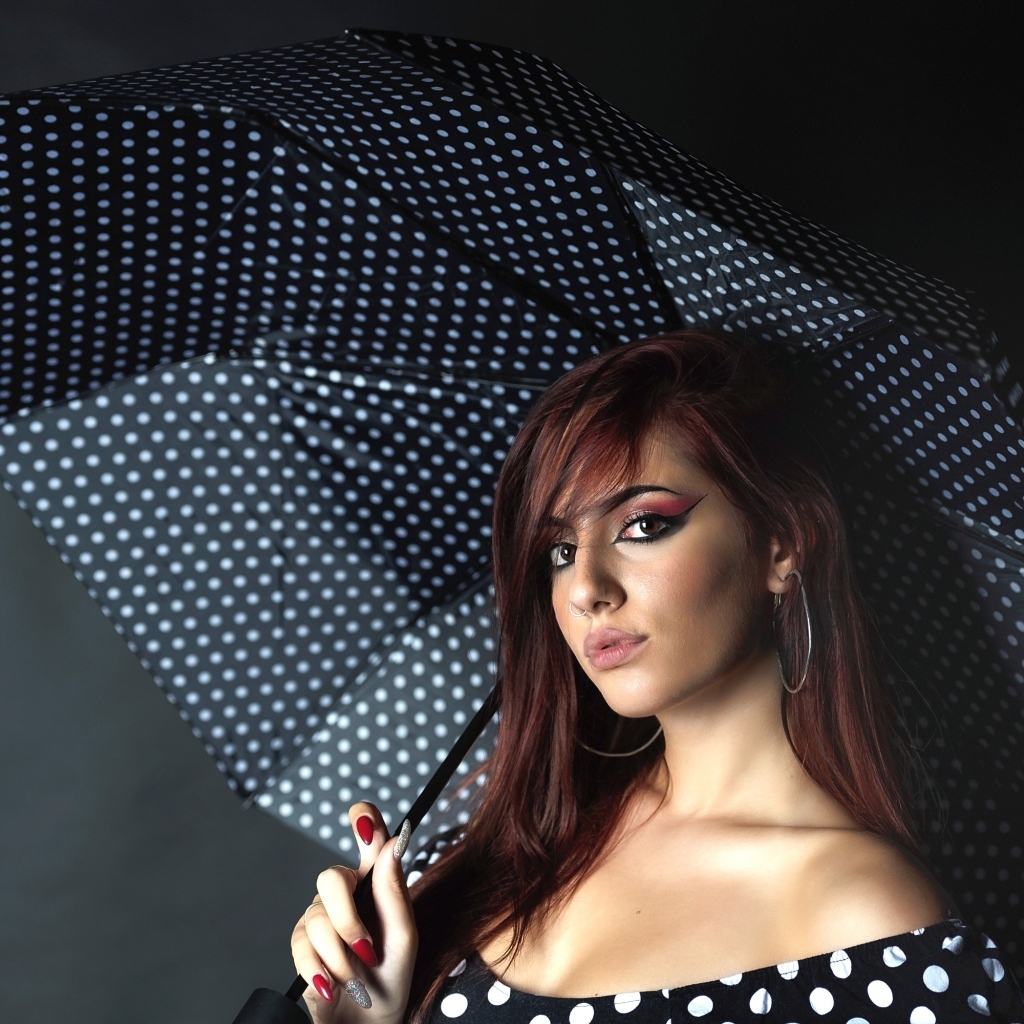 Яркая девушка под зонтом на сером фоне