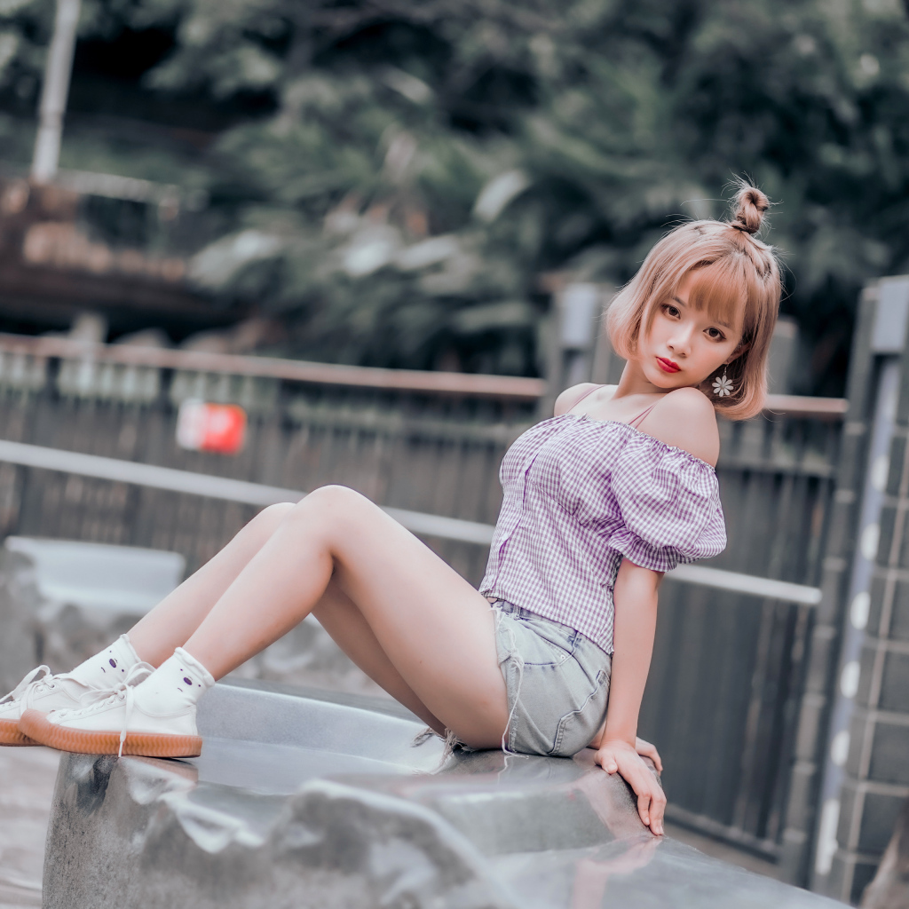 Милая девушка азиатка сидит на камне