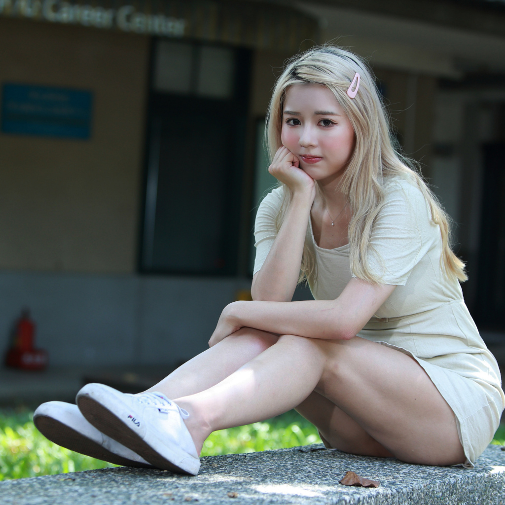 Милая азиатка сидит на холодном бетоне