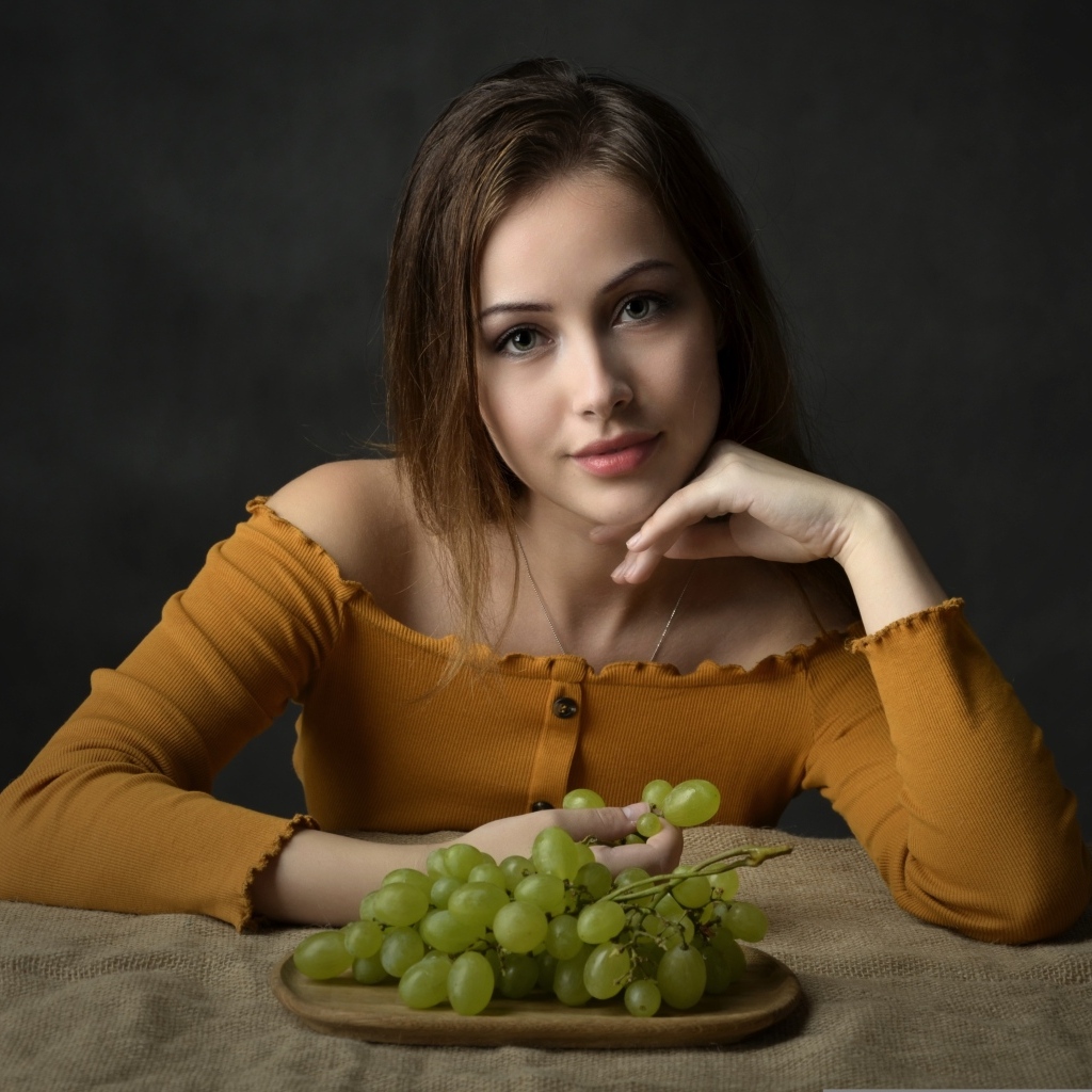 Милая шатенка ест белый виноград