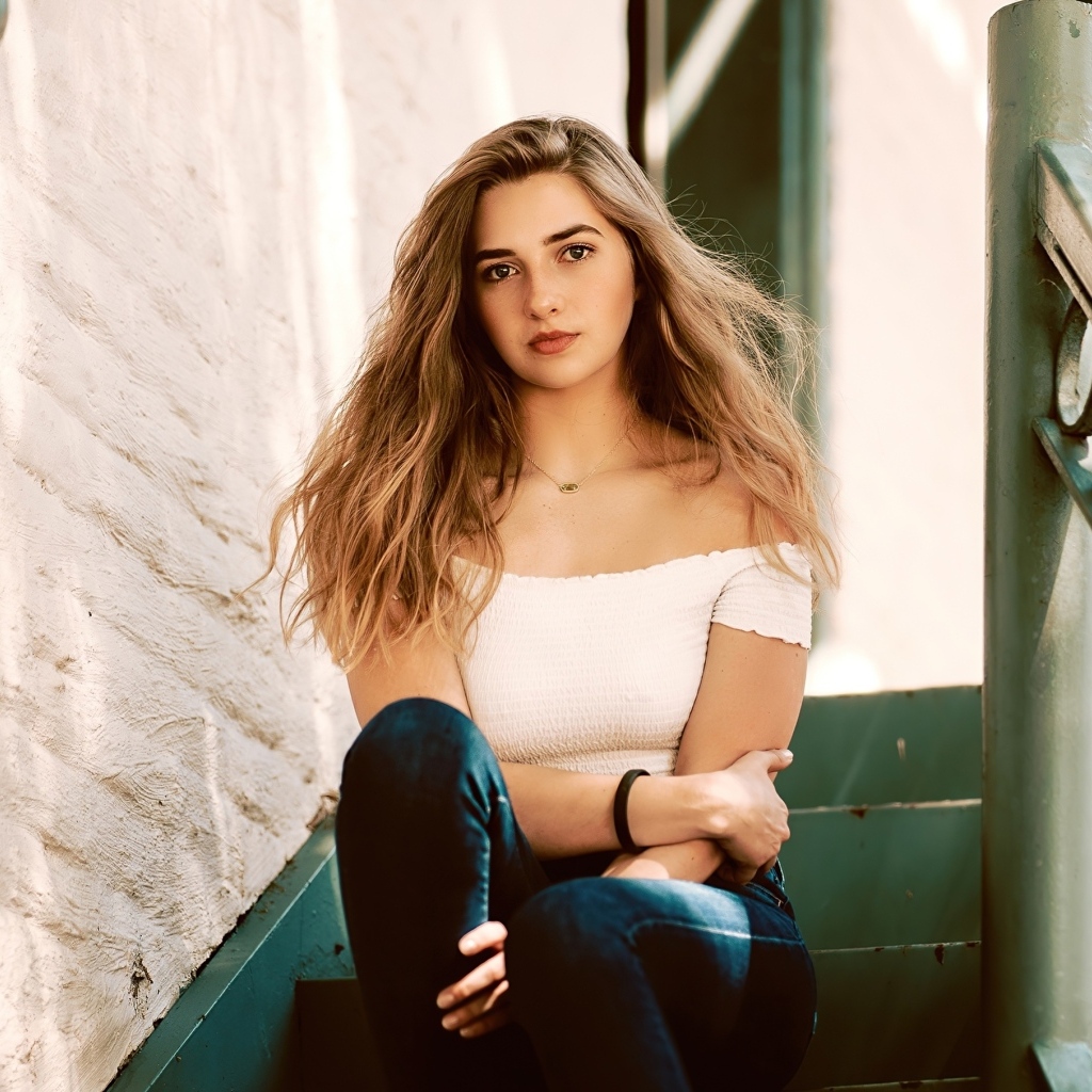 Милая девушка брюнетка сидит на ступеньках