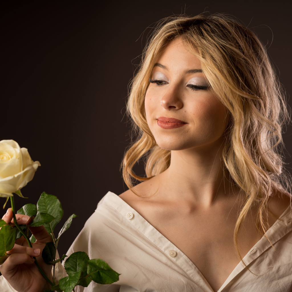 Милая девушка в рубашке с розой в руках