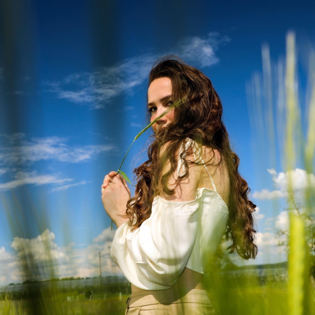 Милая девушка на поле на фоне голубого неба