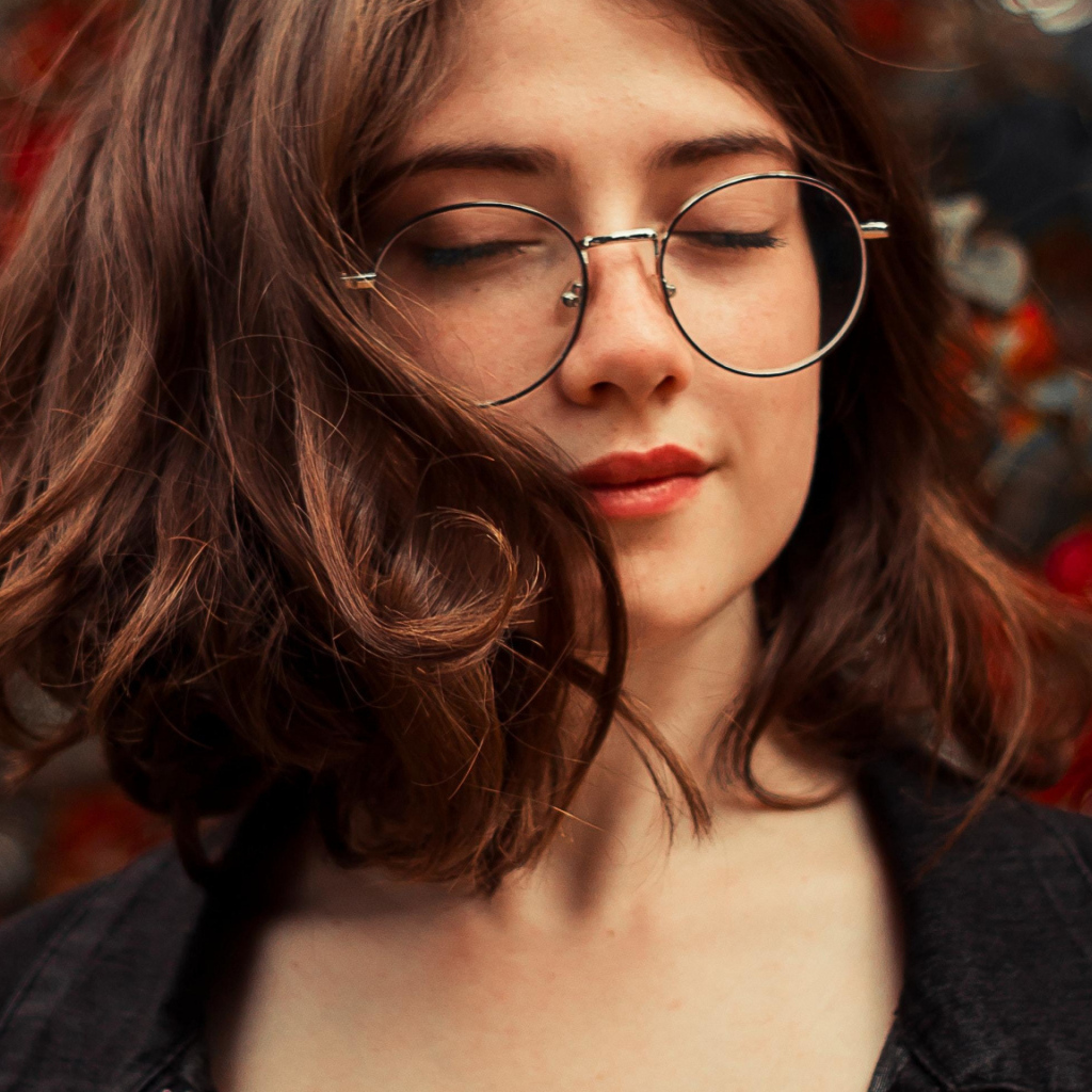 Мечтательная девушка в очках с закрытыми глазами