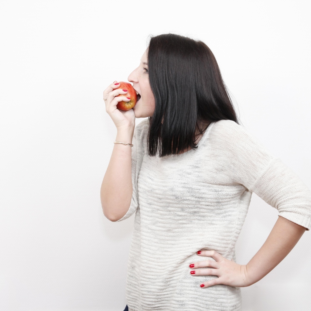 Девушка кусает красное яблоко 