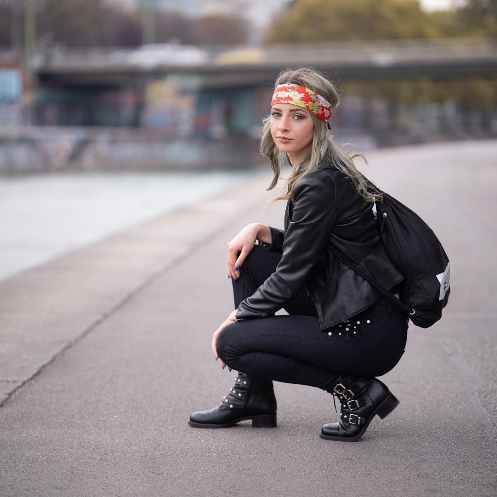 Девушка в черном костюме сидит на корточках