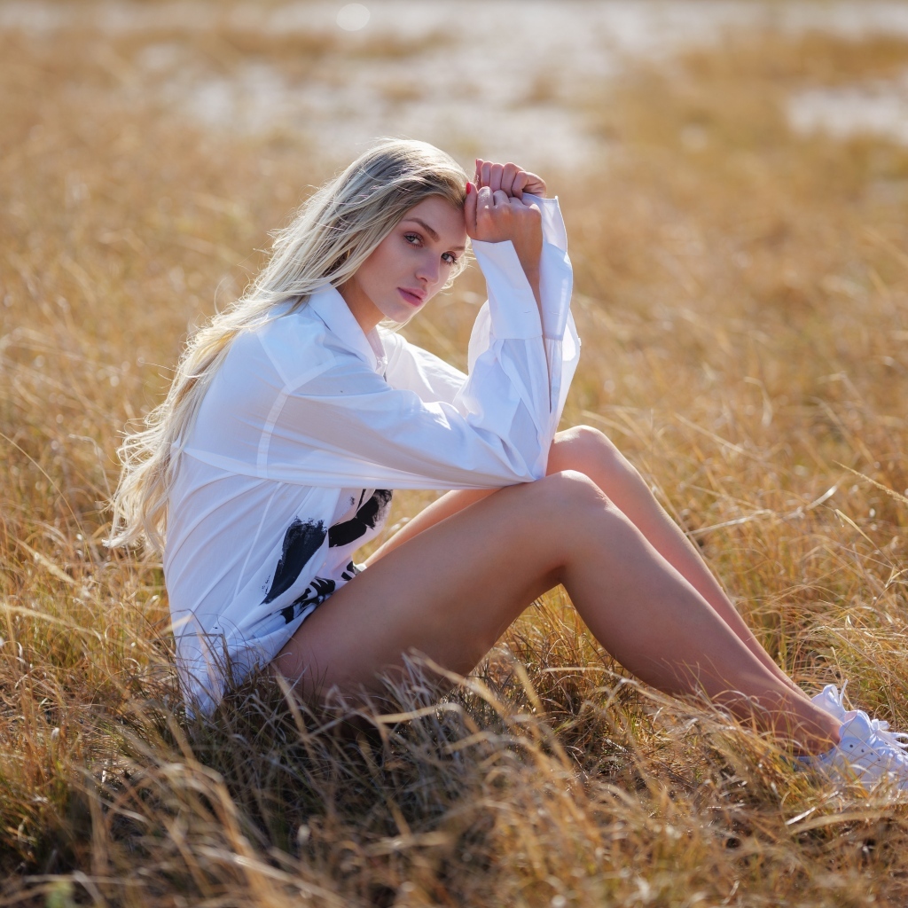Девушка в белой блузке сидит на траве