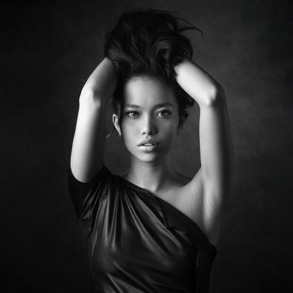 Девушка модель с руками в волосах  у стены