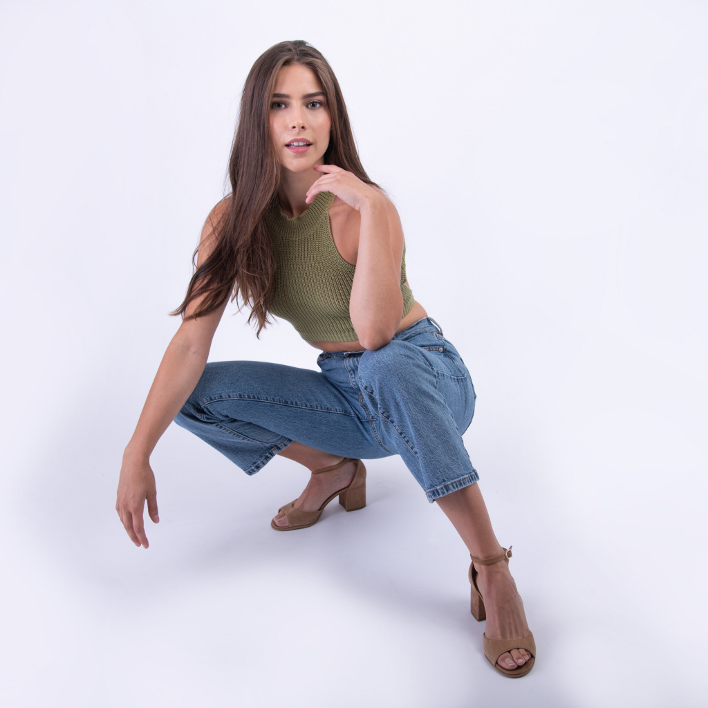 Девушка сидит на корточках на белом фоне