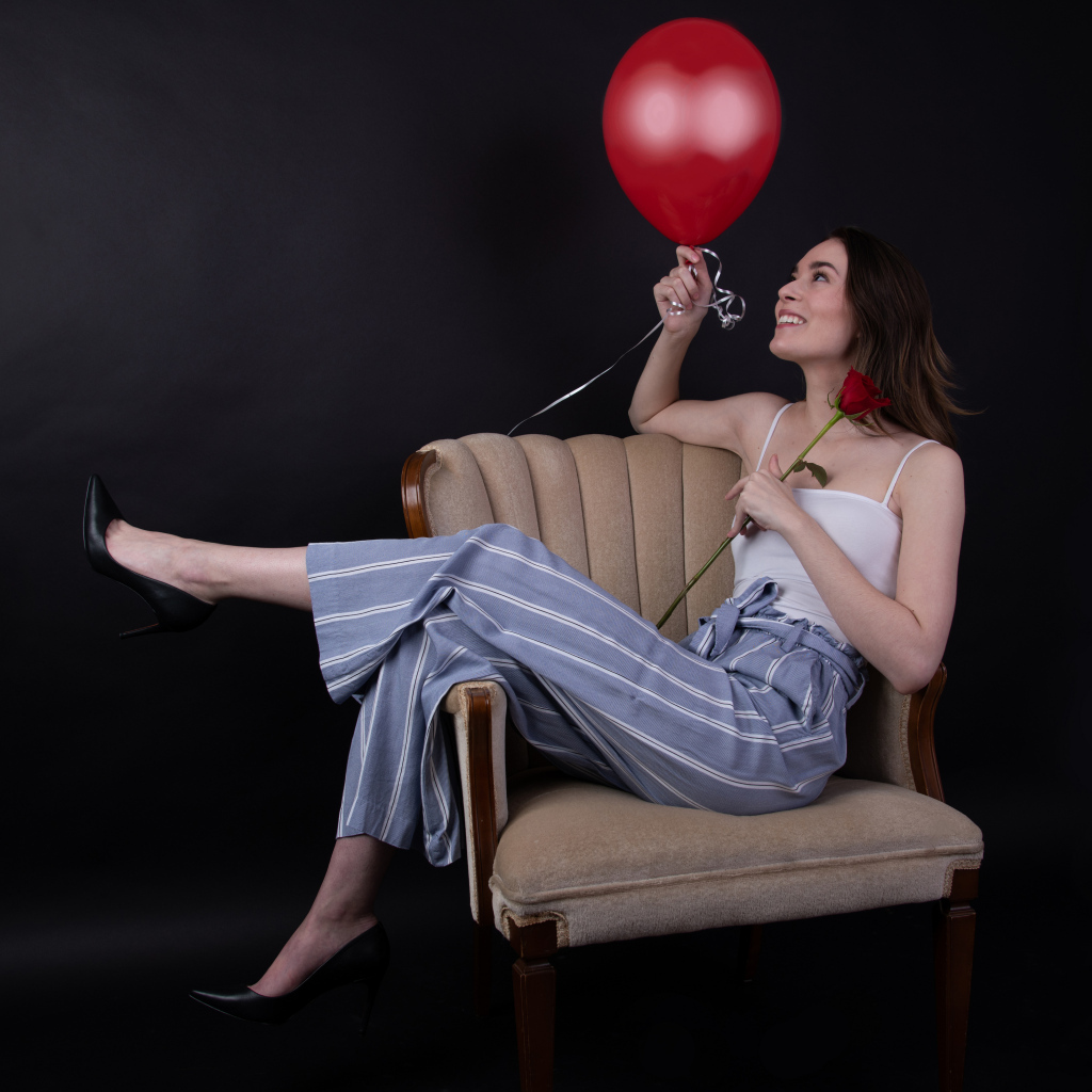 Девушка с шариком и розой сидит в кресле