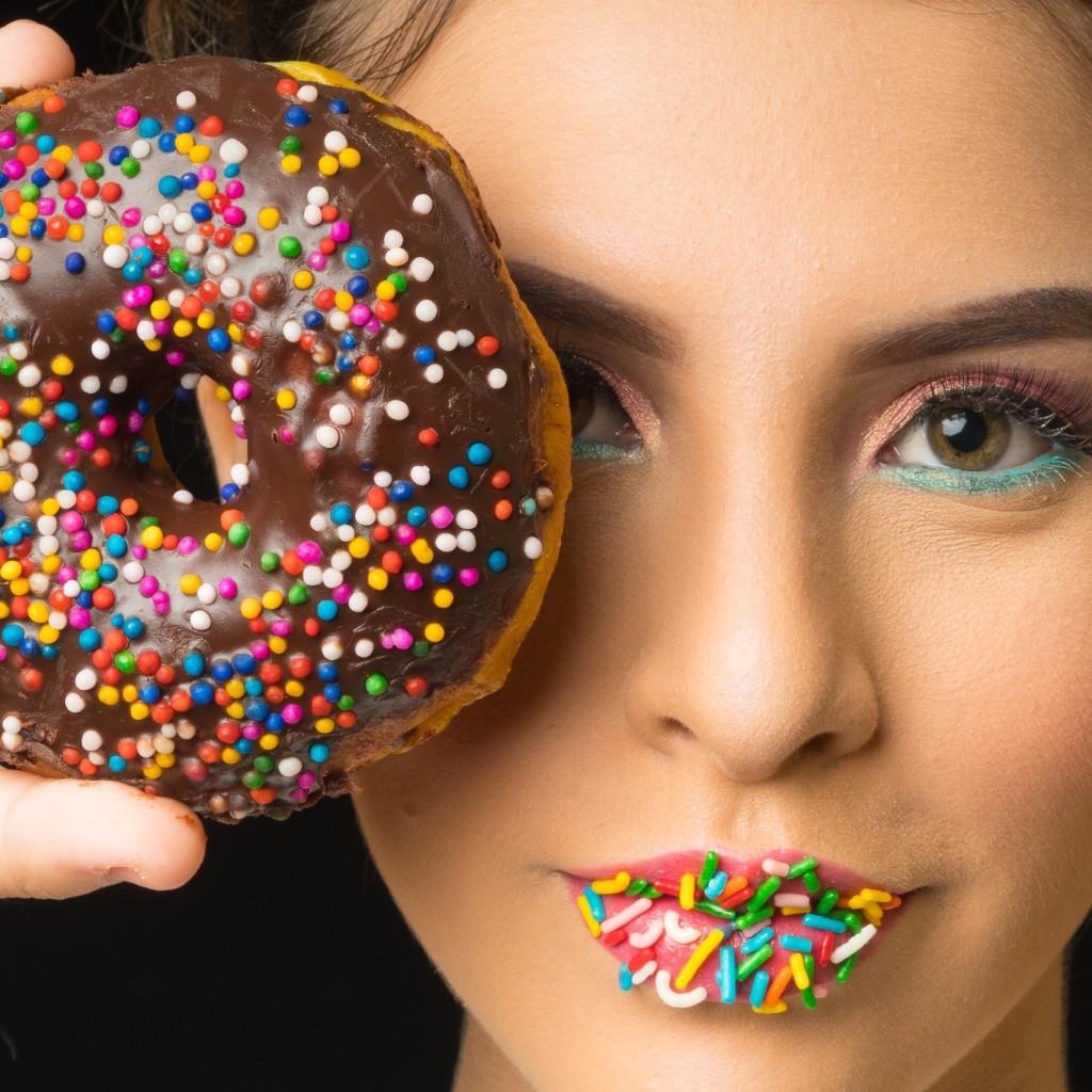 Девушка с пончиком в шоколаде в руках