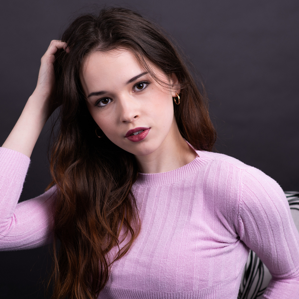 Длинноволосая шатенка в свитере с рукой в волосах