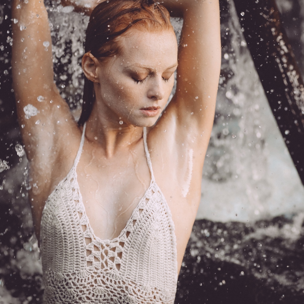 Рыжеволосая девушка в брызгах воды