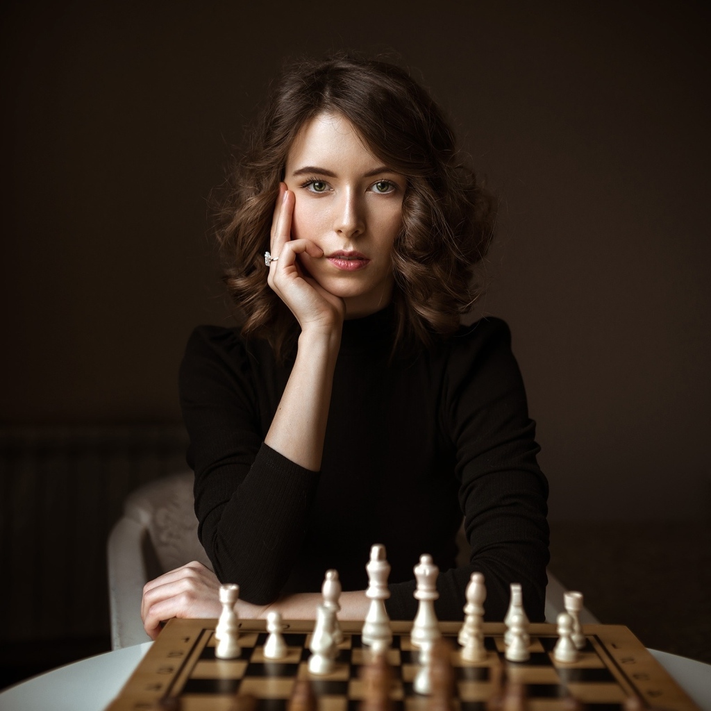 Умная молодая девушка играет в шахматы