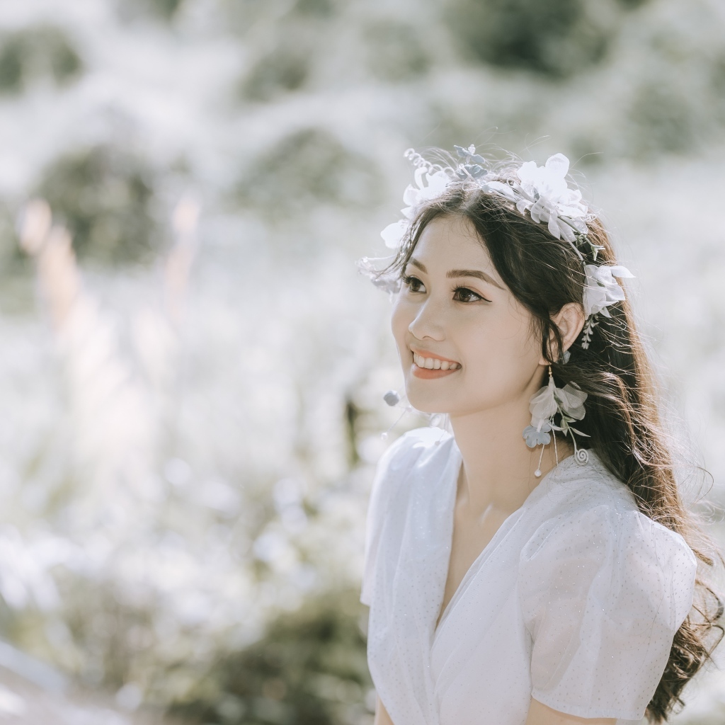 Улыбающаяся девушка азиатка в белом платье на поле