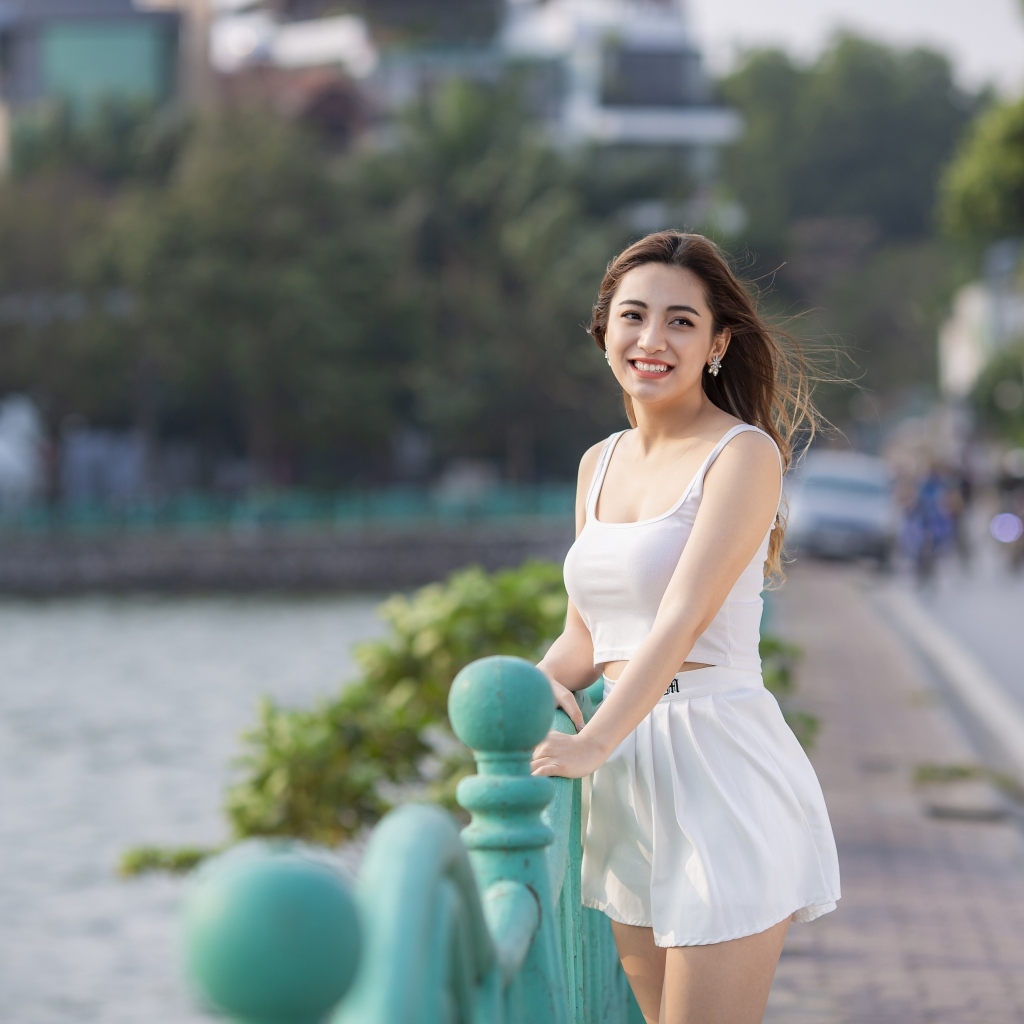 Улыбающаяся девушка азиатка в белом летнем костюме