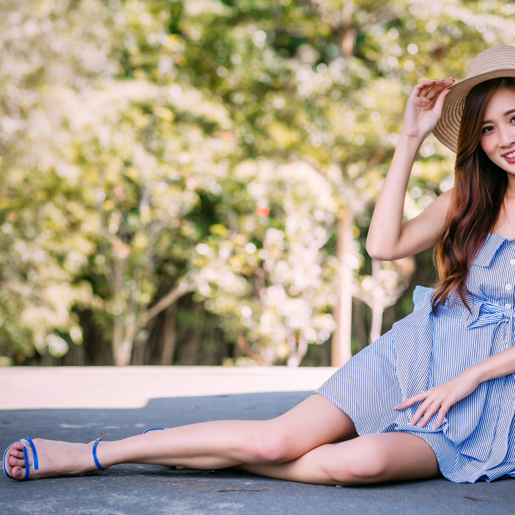 Улыбающаяся девушка азиатка сидит на асфальте